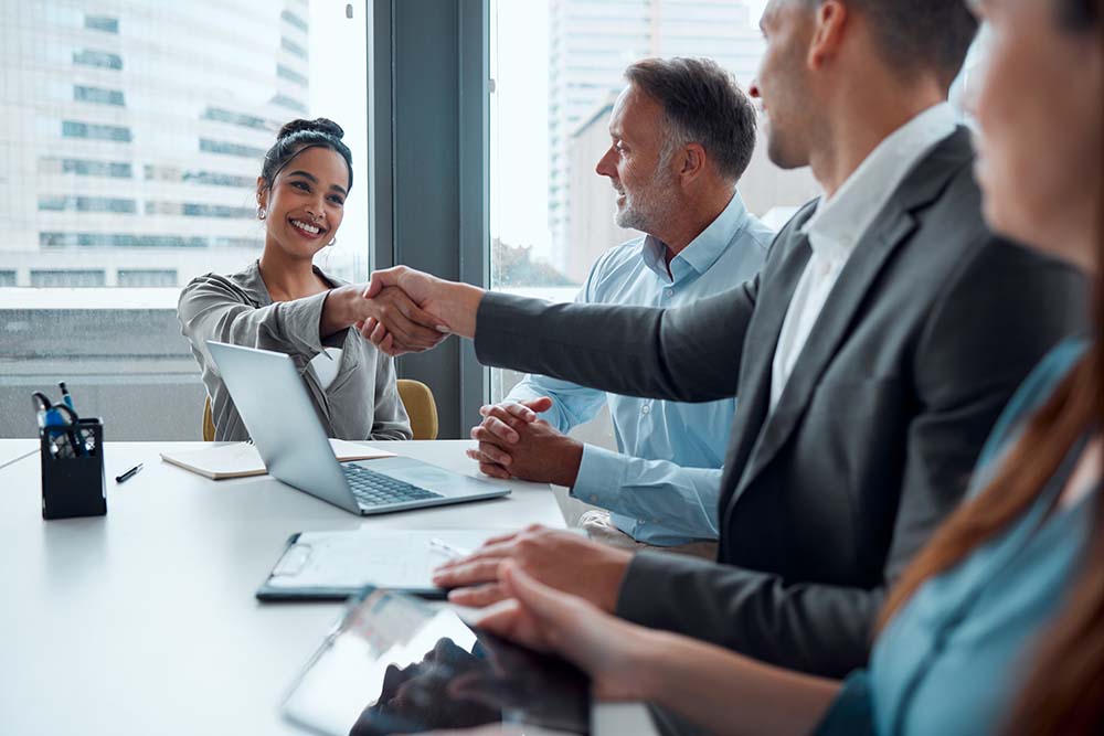 A confident handshake between two business owners across a conference table