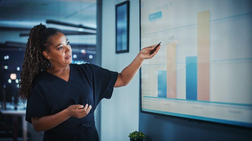 An operations director shows off a bar chart during a sales meeting