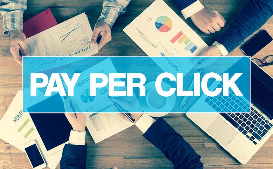A blue banner reading “PAY PER CLICK” overlayed over a business meeting scene from above, including charts and graphs