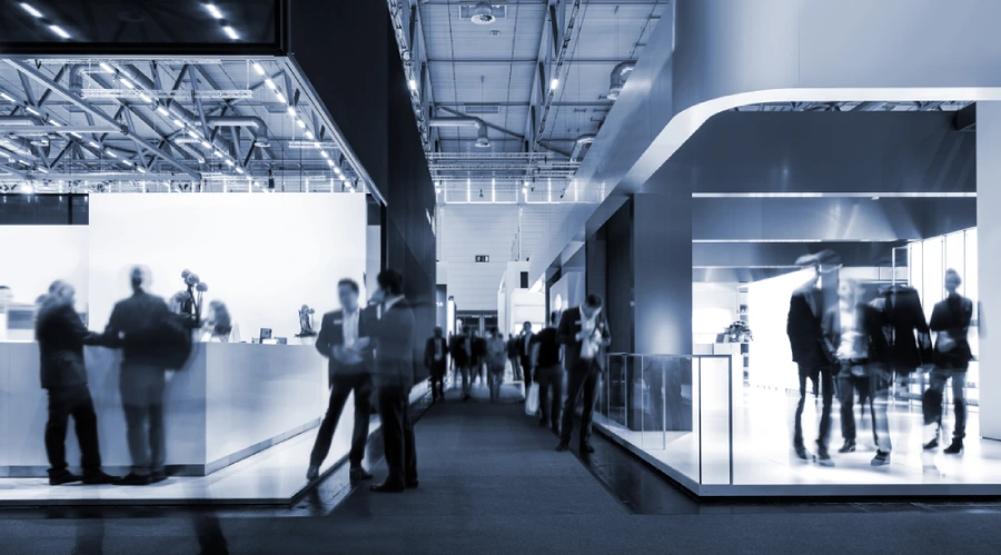 A slightly blurred black-and-white image of a busy trade show hall in motion