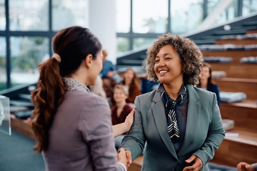 An exhibitor and attendee shake hands following an event at a business conference