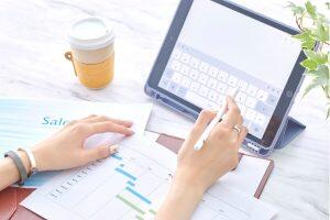 Businessperson analyzing sales data and charts on tablet with digital pen