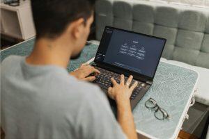 Man typing on laptop using ChatGPT AI tool at home office desk
