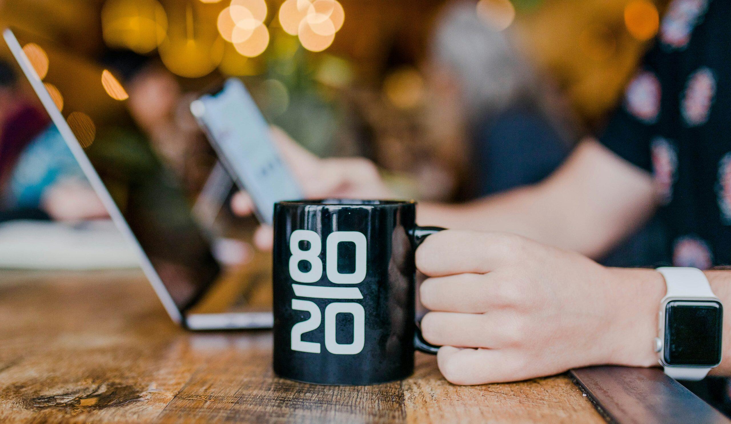 a person holding a black coffee mug with white text on it inferring The Small Business Blog helps.