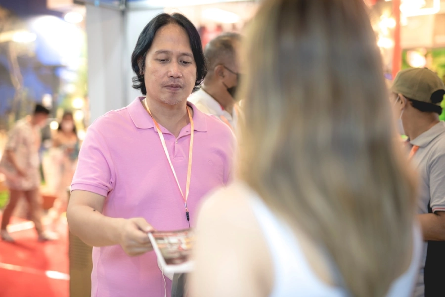 An event exhibitor hands out a brochure at a business expo