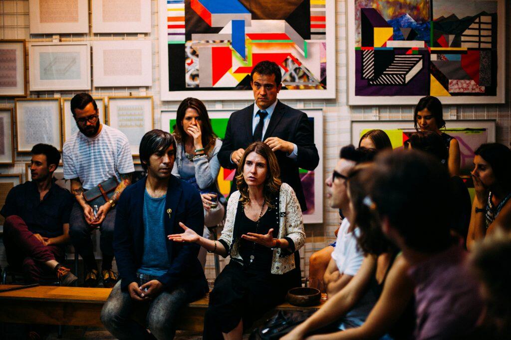 a group of people sitting in a room with art on the wall