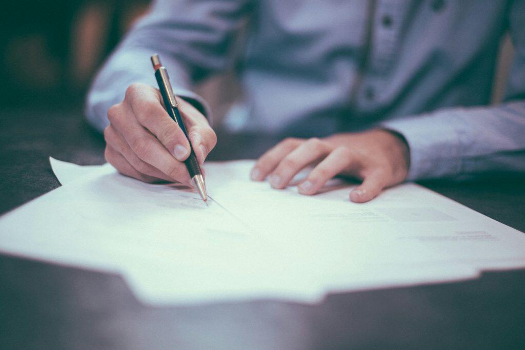 a person writing interview questions to ask candidates on a piece of paper