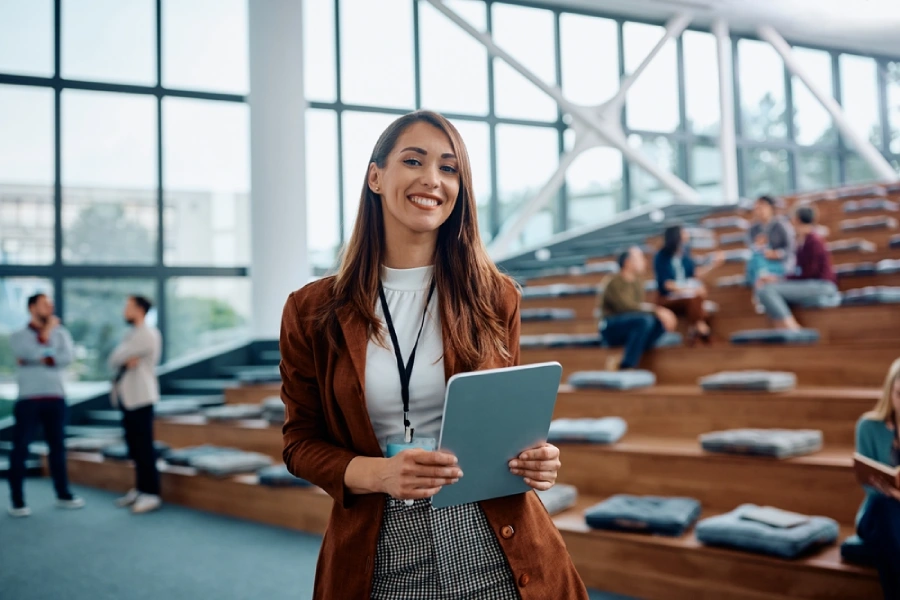 A young, female entrepreneur stands in a conference space holding a tablet