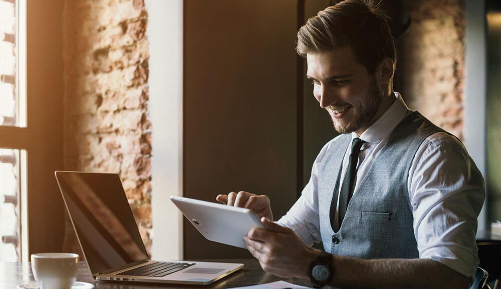 A small business owner accesses his website on a laptop and tablet